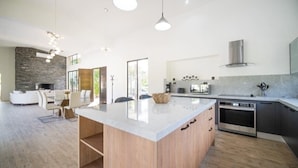 Een moderne keuken met een groot kookeiland, een inbouwoven en een accentmuur van steen.