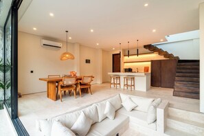 A modern interior with a dining area, kitchen, and staircase. - La Finca Villa Bingin, Uluwatu by Sandara (Pecatu)