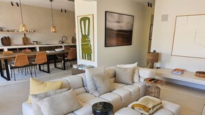 Un salon moderne avec un canapé, un coin repas avec des chaises et des œuvres d’art accrochées aux murs.