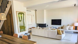 Un salon moderne avec une table à manger en bois, un canapé blanc et un grand tableau accroché au mur.