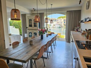 A dining area with a long wooden table, wicker chairs, and hanging wicker lamps. - Exceptional 165 m2 house with double mooring 16 m (PORT GRIMAUD)