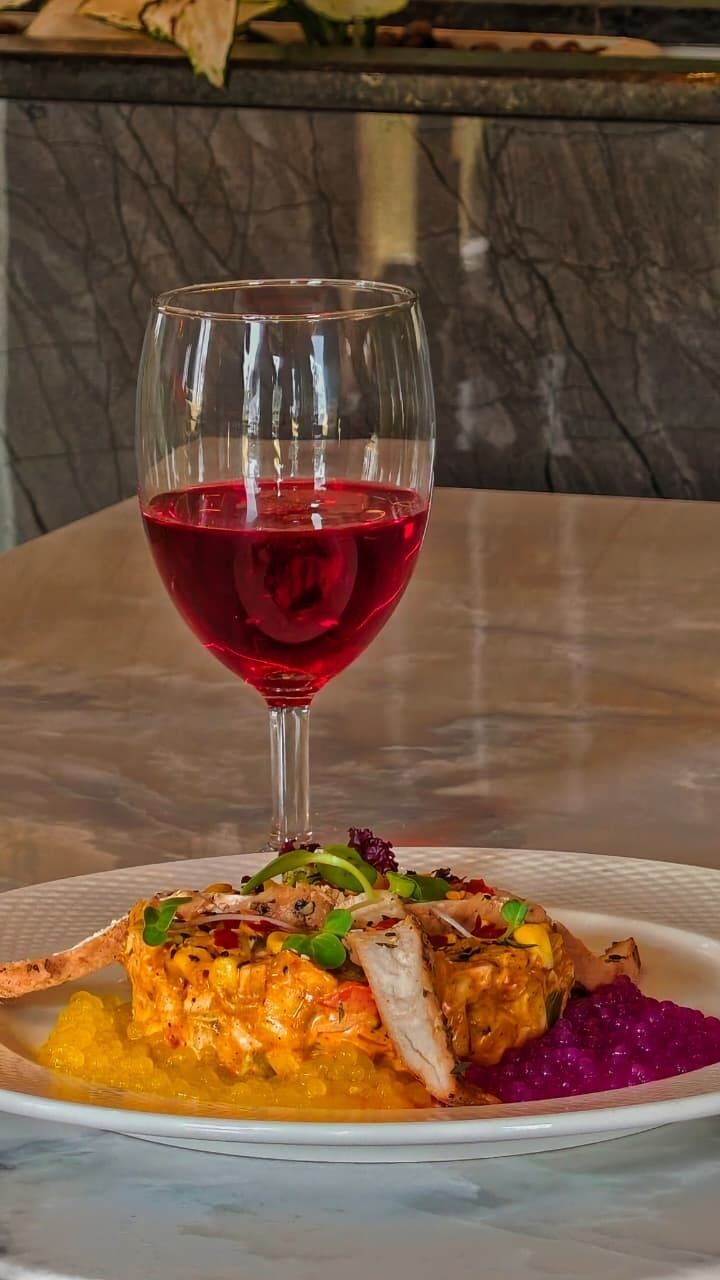 Une table à manger avec une assiette de nourriture et un verre de vin rouge.