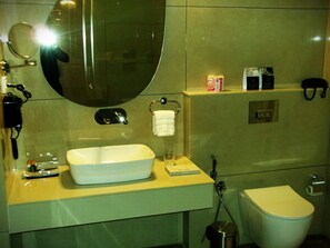 Une salle de bain équipée d’un lavabo, d’un miroir, de toilettes et d’un porte-serviettes.