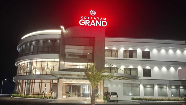 Un moderno edificio de hotel con un letrero llamativo que dice 'KOTTAYAM GRAND'.