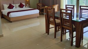 Habitación de hotel con cama, una mesa de comedor con sillas, ventilador de techo y vista a través de un ventanal grande.