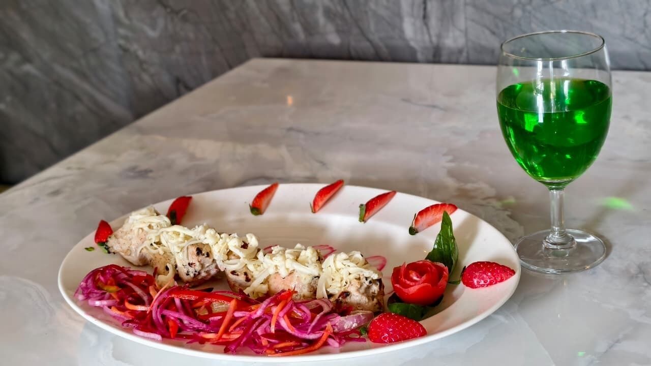 A plate of food with a glass of green drink on a marble table.