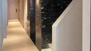 A modern hallway with wooden flooring, black marble walls, and recessed lighting. - A HOUSE SAIGON (Ho Chi Minh City)