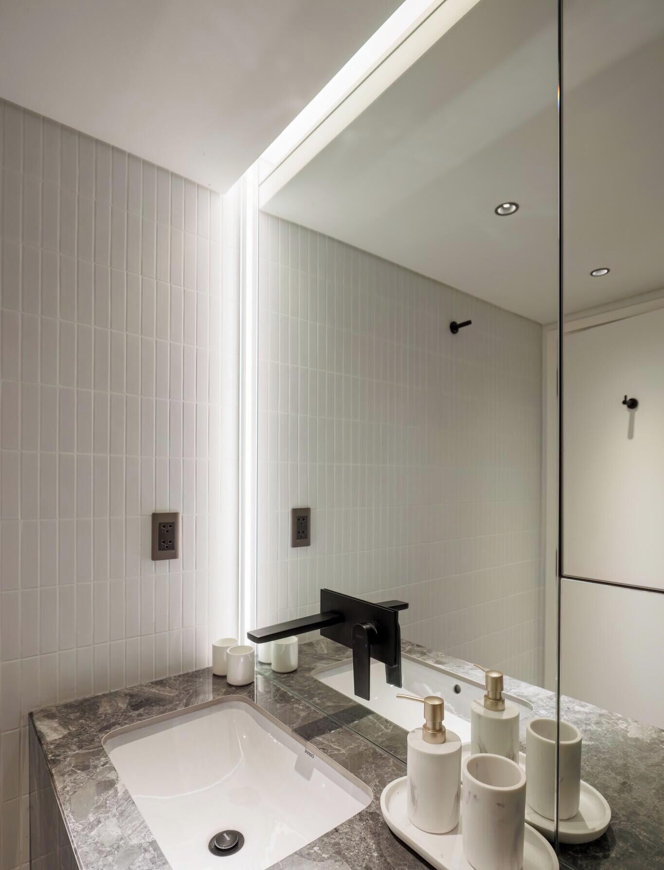 A modern bathroom with a large mirror, a black faucet, and a marble countertop.