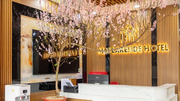 Ein Hotelrezeptionstresen mit einem großen Bildschirm, einem Wasserspender und einem Blumentopf.