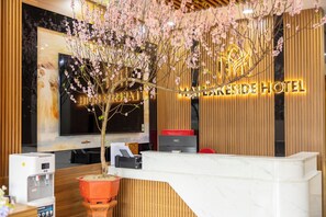 A hotel reception desk with a large screen, a water dispenser, and a potted plant. - Mai Lakeside Hotel Ninh Binh (Hoa Lu)