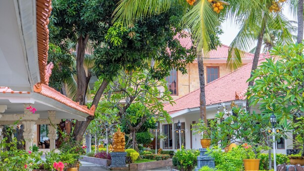 A courtyard with a central statue, surrounded by lush greenery and traditional architecture. - Grand Melka Hotel (Buleleng)