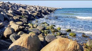 A rocky shoreline with large boulders and waves crashing onto the shore. - Ferienbungalow auf Gartengrundstück by Interhome (Bad Doberan)