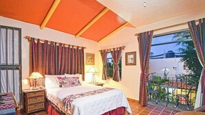 A bedroom with a bed, bedside tables, a balcony with chairs, and curtains. - Suite Steps from Malecon, Beach Dining Stripe (La Paz)