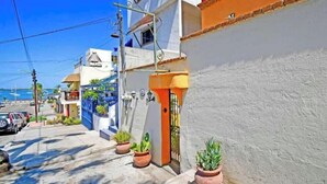 A narrow street with buildings, a gate, and potted plants. - Suite Steps from Malecon, Beach Dining Stripe (La Paz)
