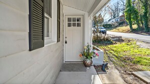 A white house with a front door, a small porch, and a potted plant with flowers. - Fabulous 5-bedroom house with AC in charming Port Republic. Walk to water/trail (Port Republic)