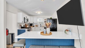 A modern kitchen with white cabinets, a central island, and a built-in seating area.