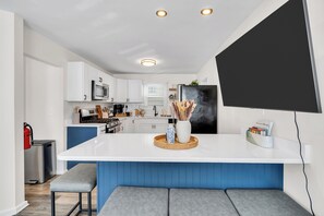 Une cuisine moderne avec des meubles blancs, un îlot central et un espace détente intégré.