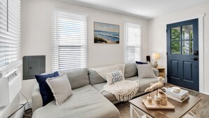 A living room with a sofa, a painting, a blue door, and a lamp.