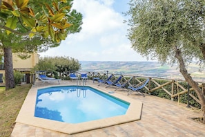 Una piscina con lettini, una recinzione in legno e vista sulla campagna.
