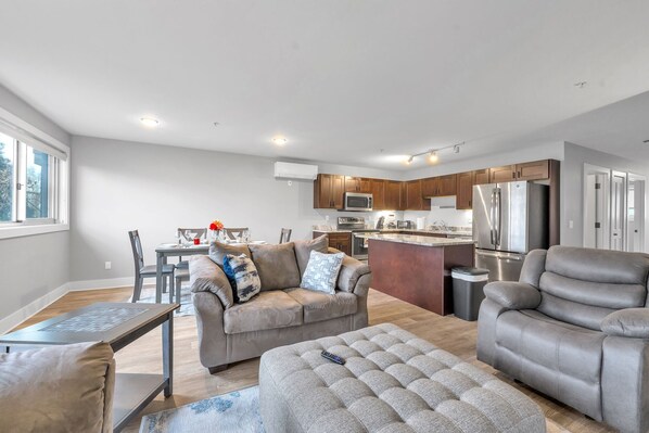A modern living room with a sofa, ottoman, and dining table. - Modern Birmingham Retreat (Birmingham)