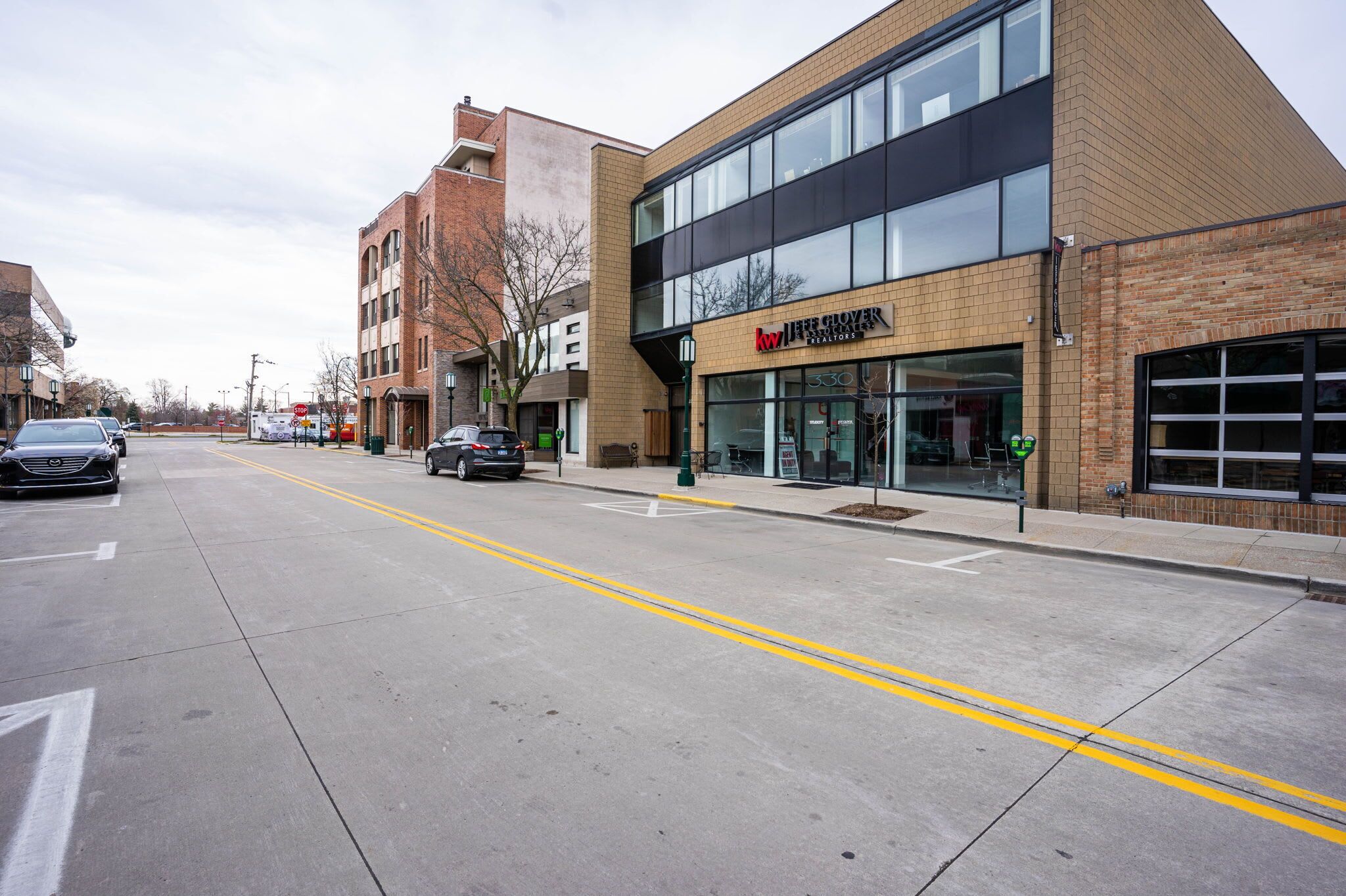 Une vue de rue avec, sur la droite, un bâtiment portant l’inscription « Jive Clover », caractérisé par une grande vitrine et une façade en briques.