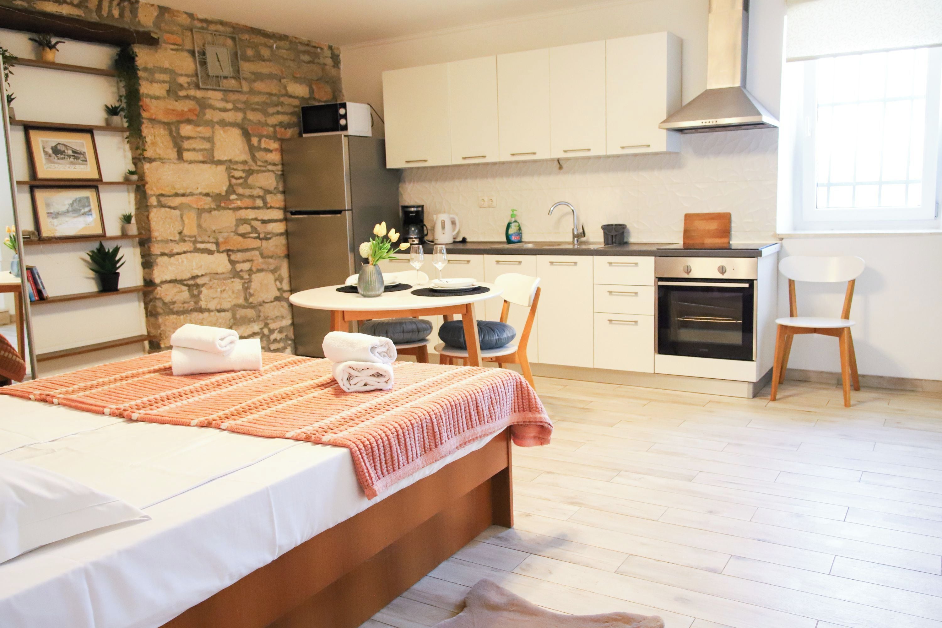 Een moderne keuken met witte kasten, een inbouwoven en een accentmuur van steen.