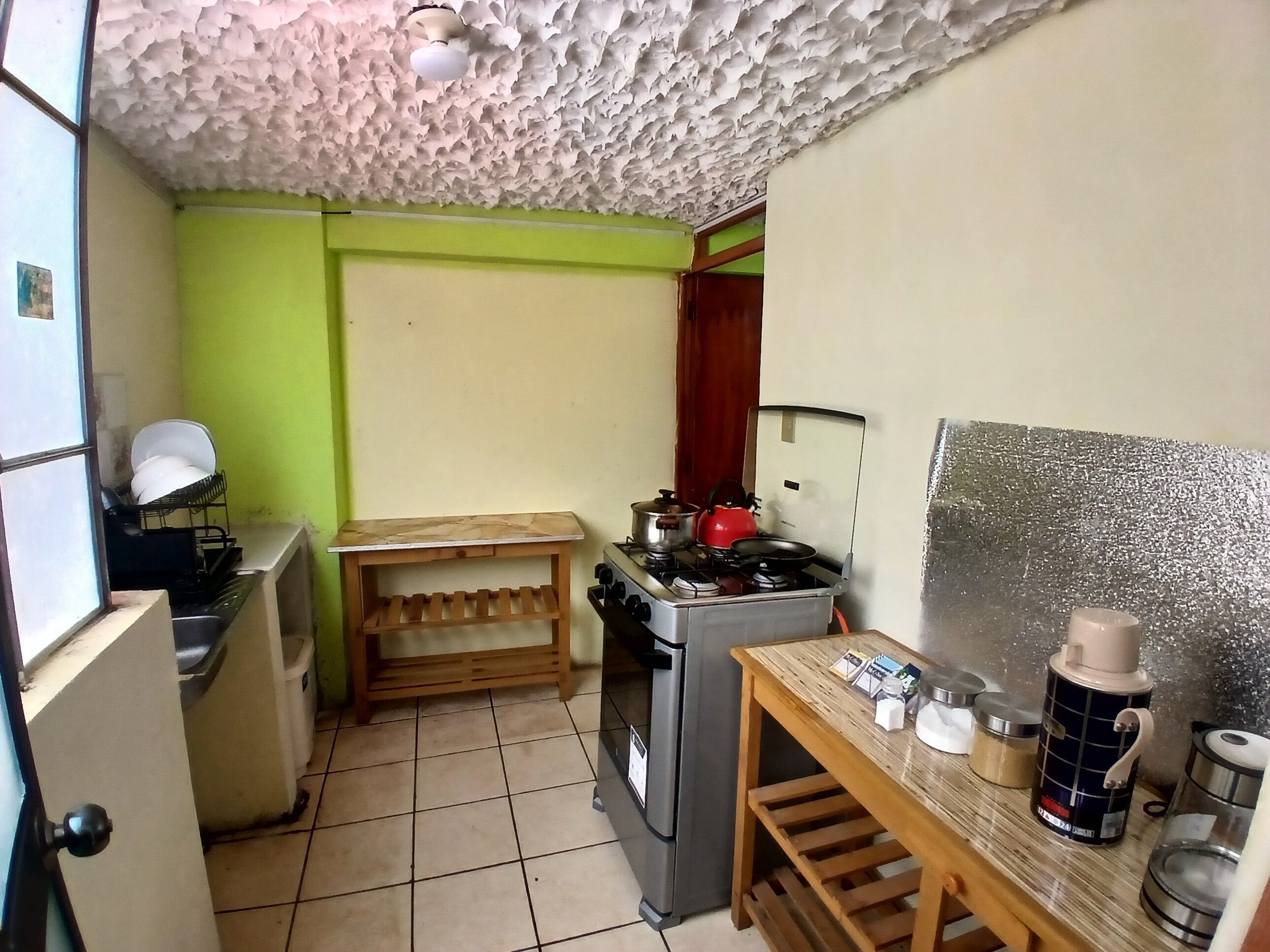 Uma cozinha compacta com fogão a gás, uma pequena mesa de madeira e uma geladeira.