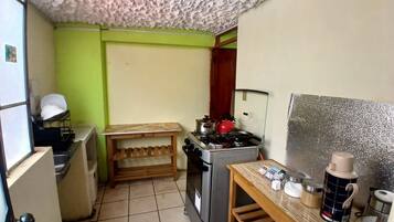 Uma cozinha compacta com fogão a gás, uma pequena mesa de madeira e uma geladeira.