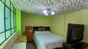 Une chambre avec un lit, une commode, un bureau et un téléviseur.