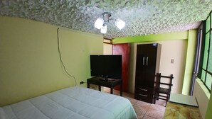 Une chambre à coucher comprenant un lit, une télévision, une armoire et un bureau.