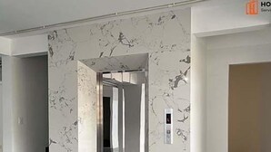A modern interior with marble walls, a staircase, and a hallway leading to another room.