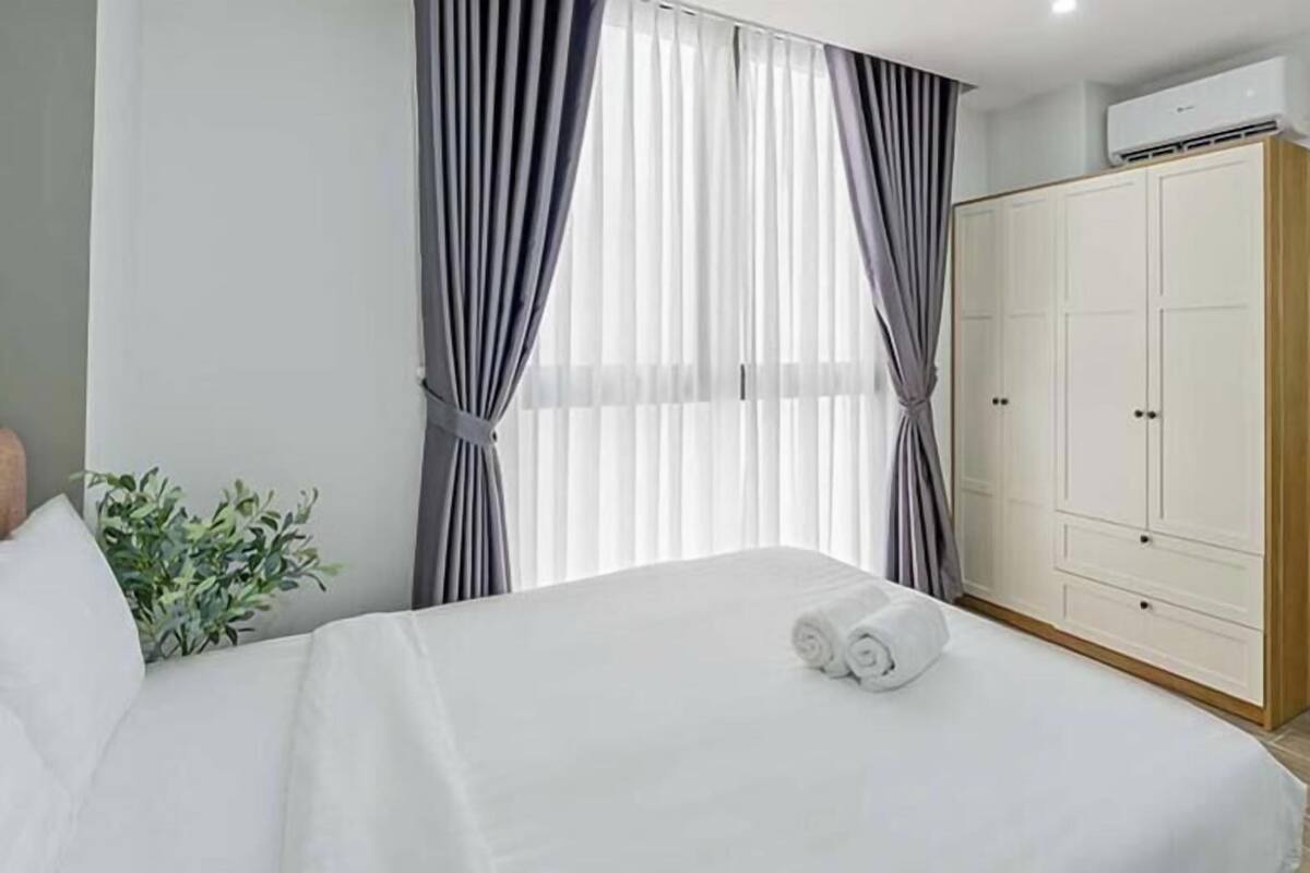 Habitación de hotel con cama, armario, baño con lavabo y espejo, y una planta en maceta.