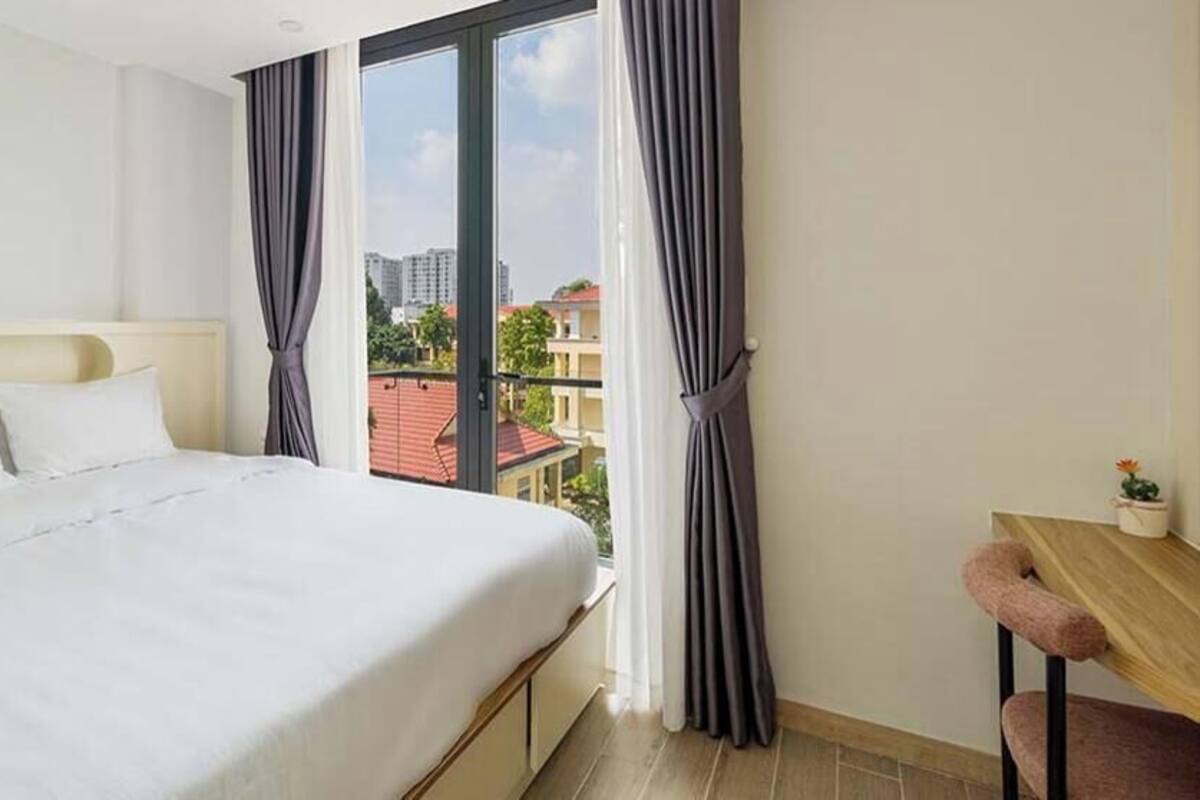 Un dormitorio con cama, escritorio y ventana con cortinas.