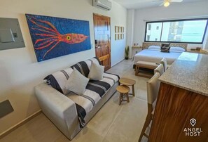 Ein modernes Hotelzimmer mit einer Couch, einem kleinen Tisch, einem Bett und einem großen Fenster.