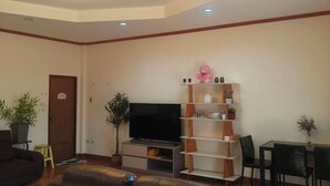 A living room with a sofa, a TV, a bookshelf, and a dining area. - wilderness Plus (Ban Chang)