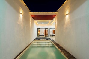 A swimming pool with a view of a bedroom and bathroom through glass doors. - Ghania Villas Melasti (Ungasan)