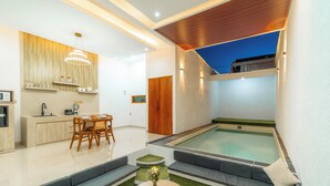 A modern living area with a pool, seating, and a kitchen. - Ghania Villas Melasti (Ungasan)