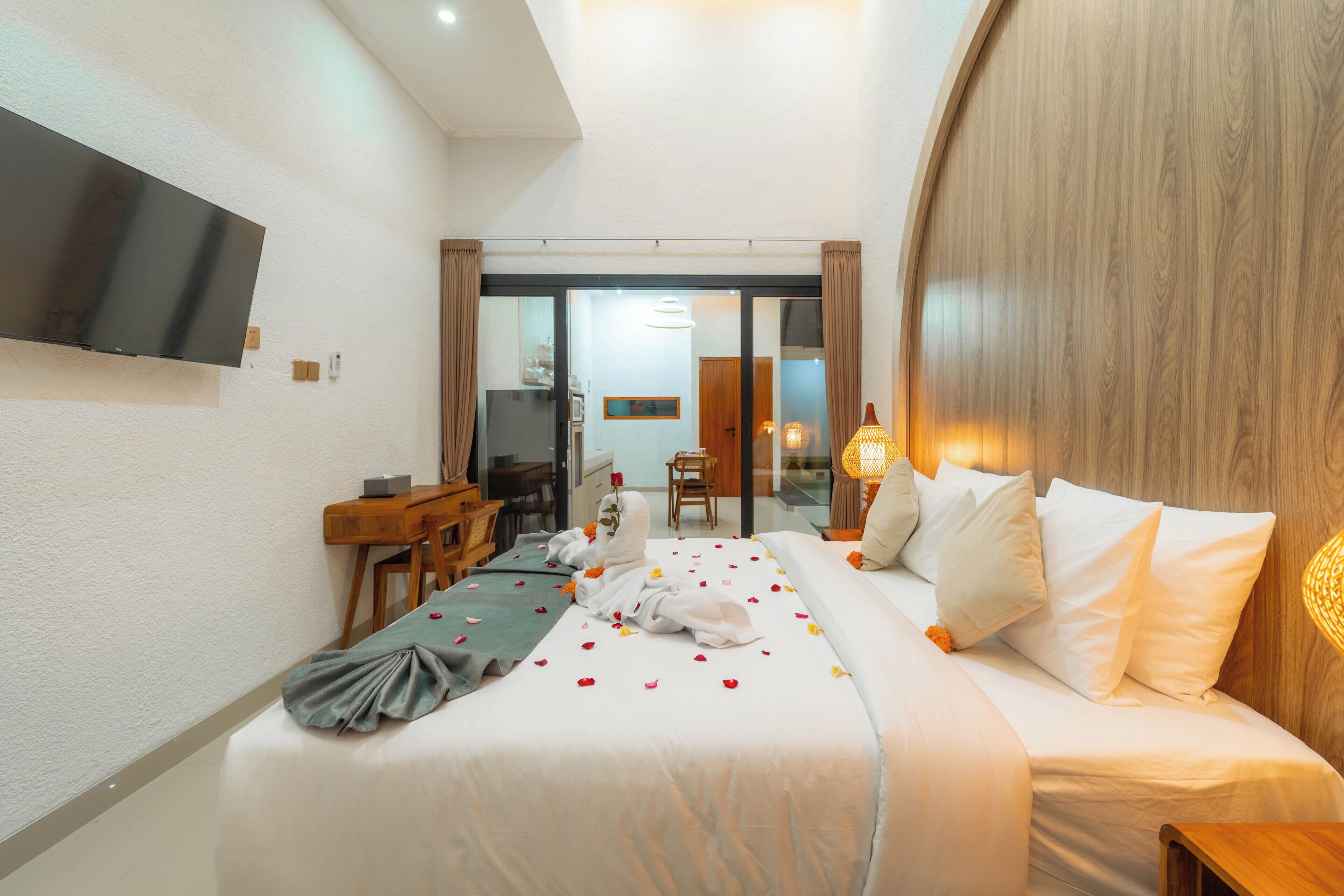 A hotel room with a bed, a desk, a chair, a television, and a sliding door to a bathroom.