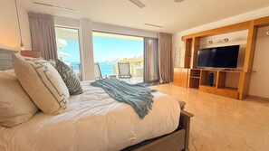 Un dormitori amb un llit gran, televisió i vistes al mar.