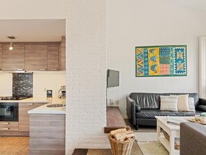 A modern kitchen with wooden cabinets, a built-in microwave, and a central island. - Nice beach house directly by the sea with garden (Nieuwvliet)
