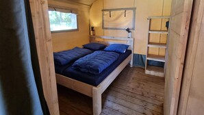 Un lit superposé en bois, avec une fenêtre, une échelle et une étagère.