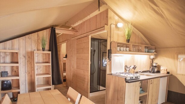 Une cuisine de taille réduite, dotée de meubles de rangement en bois, d’une cuisinière à gaz et d’un évier.