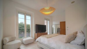 A bedroom with a bed, a TV, a chair, and a large window. - 13491130 FRGK French Riviera Villa with Private Pool AC (Cannes)