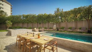 A poolside area with a dining table set for six, a pool, and a low wall with trees and a building in the background. - 13491130 FRGK French Riviera Villa with Private Pool AC (Cannes)
