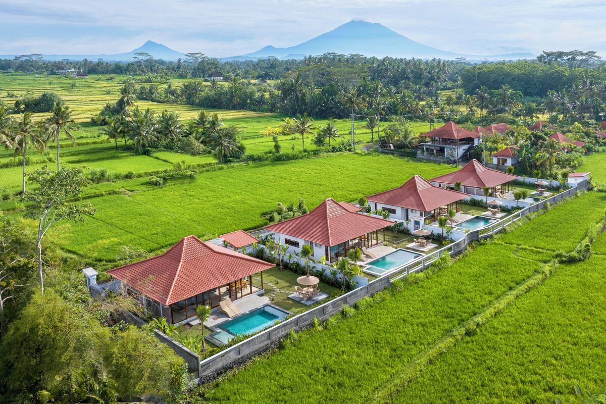 A resort with multiple villas, a swimming pool, and lush green fields.