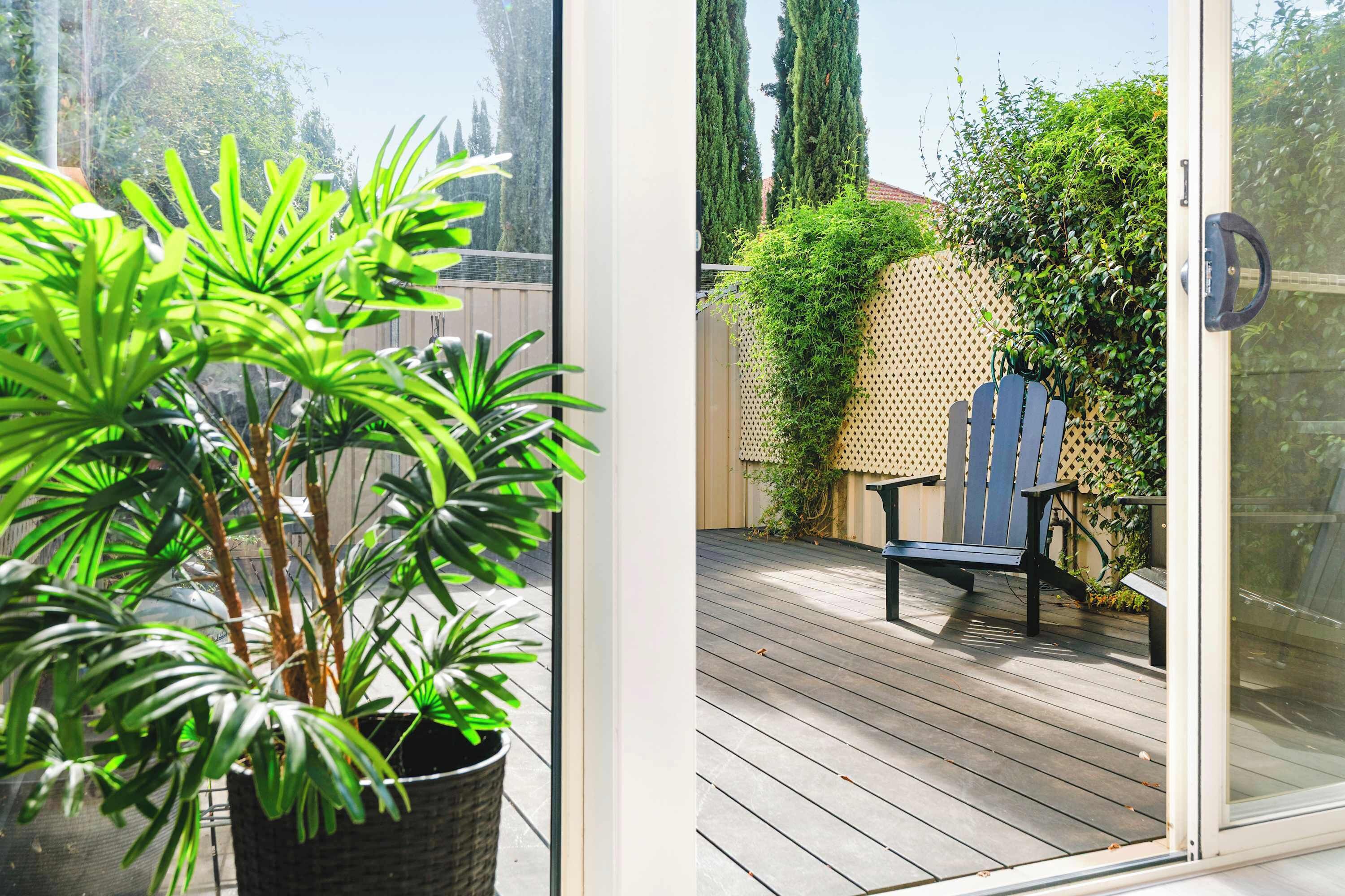Une terrasse en bois avec une chaise et un pot de fleurs.