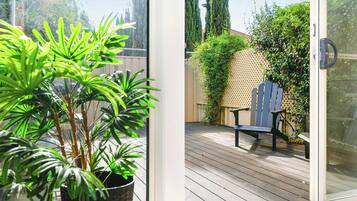 Une terrasse en bois avec une chaise et un pot de fleurs.