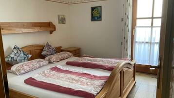 A bedroom with a wooden bed, pillows, a nightstand, a wall-mounted shelf, and a painting.