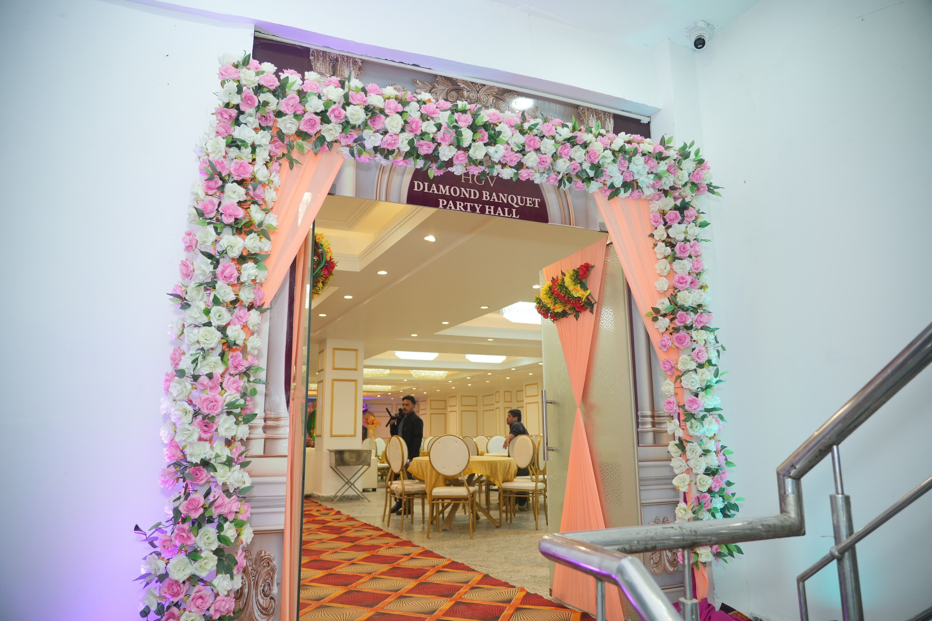 An entrance to a banquet hall with a floral archway and a sign indicating it's a Diamond Banquet Party Hall. - Hotel Golden Valley (Faridabad)