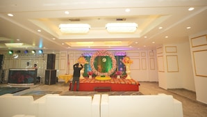 A stage with a floral backdrop, a podium, and a large screen. - Hotel Golden Valley (Faridabad)